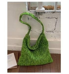 Detail van groene tweed hobo tas met grove gebreide textuur en zwart geweven label