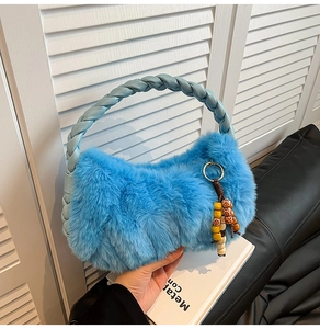 Detail of blue plush handbag with braided leather handle and colorful beaded charm