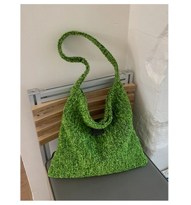 Detail van groene tweed hobo tas met getextureerde wol en een zwart mode-etiket