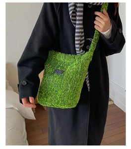 Detail der grünen Plüsch-Beuteltasche mit Fashion-Label, von einem Model getragen