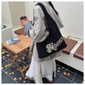 Close-up of black knitted tote bag with leopard print patch in a cozy autumn street setting