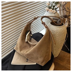 Détail du sac hobo en daim avec pompon de perles colorées et garnitures vintage