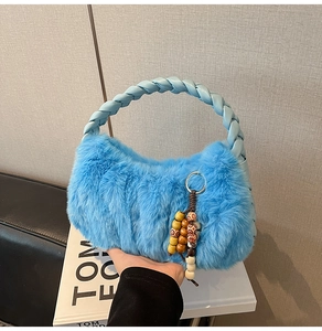 Detail of blue plush handbag with woven leather handle and colorful beaded charms