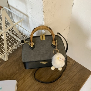 Detailed view of the bamboo handle and shell-shaped bag with a plush lamb pendant