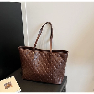 Detail view of brown quilted tote bag with golden studs and reinforced dual handles