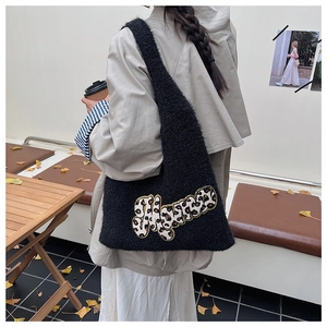 Detail of black plush shoulder bag featuring a stylish leopard print letter patch design
