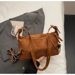 Detail of brown suede dumpling bag featuring knotted strap and metal eyelets