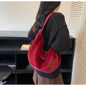 Detailed texture of a red faux fur hobo bag with matching leather shoulder strap worn by a model