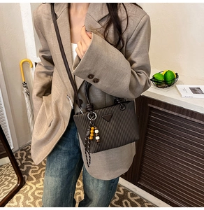 Détail du sac seau plissé marron foncé avec plis verticaux et breloque perlée