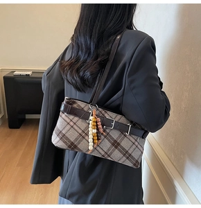 Detail of vintage plaid underarm bag with leather strap and wooden bead charm