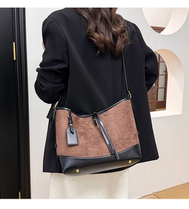 Brown suede and black leather patchwork bucket bag shown on model for style context