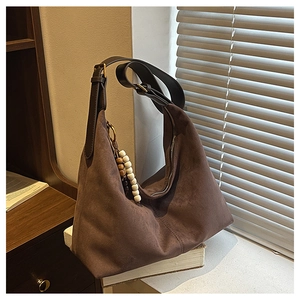 Gros plan du sac cabas en daim marron avec bandoulière en cuir et breloque décorative