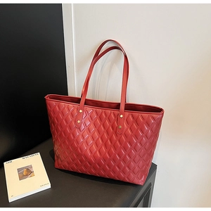 Detail of red quilted tote bag with large capacity and elegant gold metal rivets