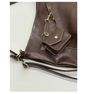 Détail du grand sac cabas en cuir marron avec coutures blanches et mini-pochette