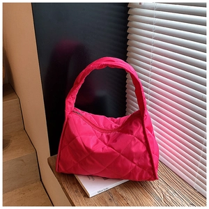 Vibrant pink quilted shoulder bag with diamond stitching on a modern wooden display