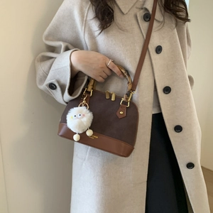 Detail of crossbody bag with bamboo handle, faux suede fabric and white plush charm