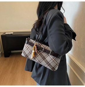 Detail of plaid shoulder bag featuring vintage checkered fabric and dark brown leather strap