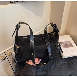 Detail of black suede dumpling bag featuring golden metal eyelets and premium texture