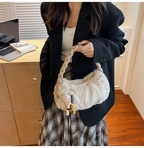Close-up of beige plush handbag with braided handle and wooden bead charm in office setting