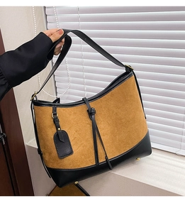 Detail shot of the two-tone bucket bag with suede texture and adjustable strap