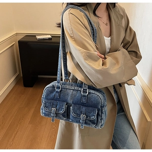 Detail of vintage blue denim shoulder bag with double buckle pockets and slim straps