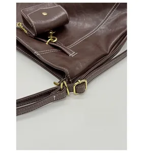 Détails de la ferrure rétro et surpiqûres blanches sur ce sac fourre-tout marron