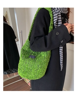 Detail der leuchtend grünen Plüschtasche mit schwarzem Label zum schwarzen Wollmantel