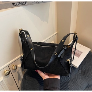 Detail of black suede handbag featuring gold hardware and adjustable eyelet strap