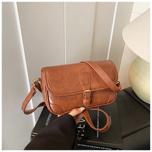 Detail of vintage brown textured leather satchel featuring a classic buckle flap closure