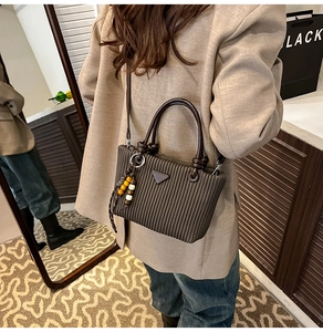Détail du sac seau plissé marron foncé avec plaque triangulaire et pendentif perlé