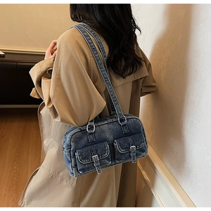 Detail of denim shoulder bag featuring double front pockets and metallic buckles