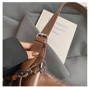 Detail of adjustable leather shoulder strap with beads on a vintage brown crossbody bag