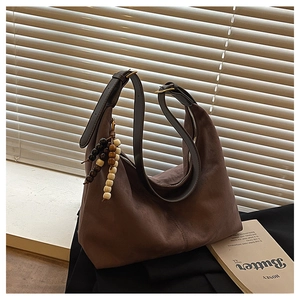 Détail du sac hobo en daim avec large bandoulière en cuir et perles en bois