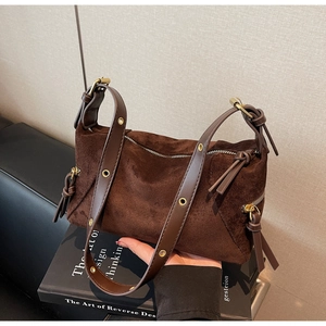 Detail view of coffee suede leather dumpling bag featuring gold metal eyelets and zipper
