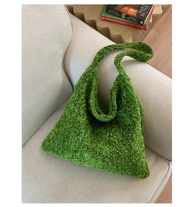 Detail van de groene boucle stoffen shopper op een minimalistische beige bankachtergrond