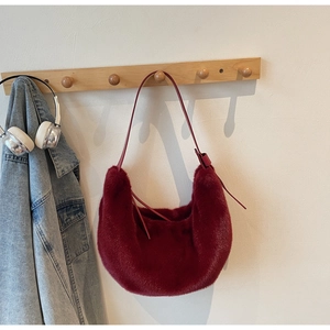 Detail of burgundy faux fur hobo bag with slim leather strap and metal buckle