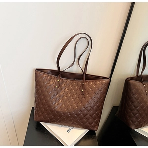 Detail view of large dark brown quilted tote bag with refined gold rivet hardware accents