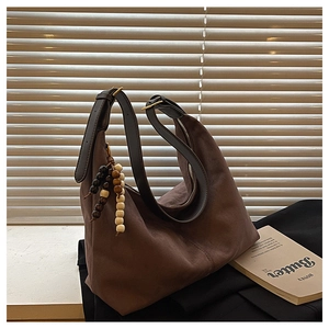 Detail of dark brown suede tote bag with leather strap and wooden bead charm detail