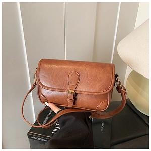 Detail shot of a brown vintage leather shoulder bag with a metal buckle and adjustable strap