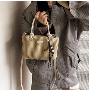 Détail du sac en velours côtelé beige avec poignée nouée et plaque en métal triangle