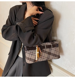 Detail of vintage plaid underarm bag with decorative wooden beads and leather strap