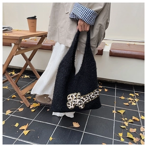 Detail of black fuzzy knit tote bag with leopard print embroidery in an autumn cafe setting