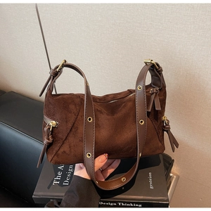 Detail of vintage brown suede dumpling bag featuring leather tassels and metal eyelets