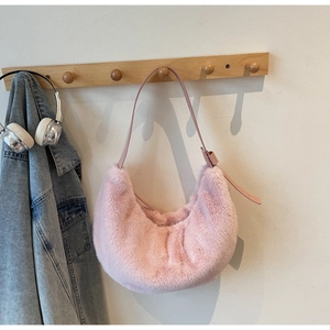 Detail of pink faux fur crescent shoulder bag featuring adjustable leather strap on wood hook