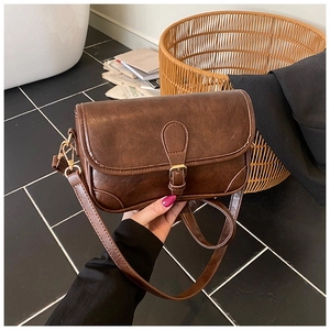 Close-up of vintage dark brown faux leather shoulder bag with gold buckle detail