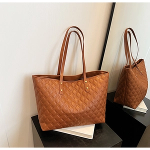 Detail of brown quilted tote bag with large capacity and reinforced gold rivet straps
