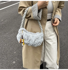 Detailed view of light gray plush handbag with braided strap and colorful bead charm