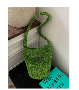 Detail einer grünen Plüsch-Beuteltasche mit weichem Strukturstoff und Mode-Label