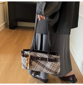 Close-up of retro plaid underarm bag with leather strap and wooden bead charm detail