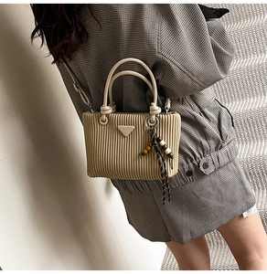 Détail du sac seau en velours côtelé beige avec logo triangle et pompon en perles